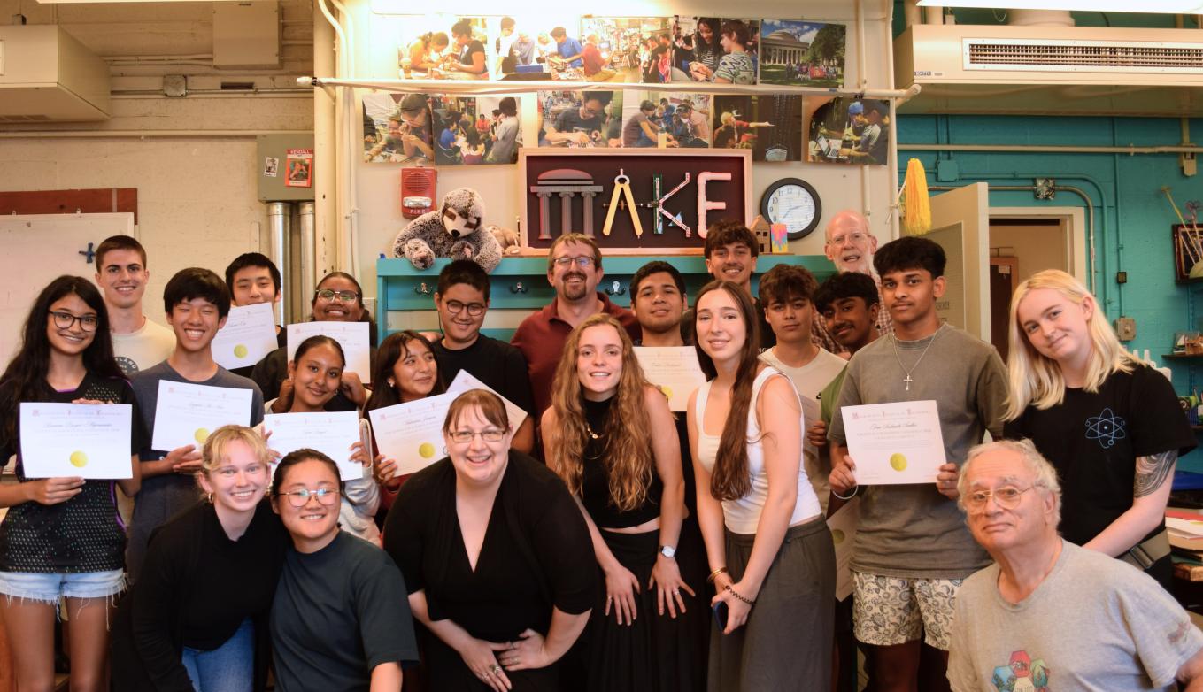 Edgerton Hackathon Challenge participants hold their certificates and smile in the 4-409 Makerspace