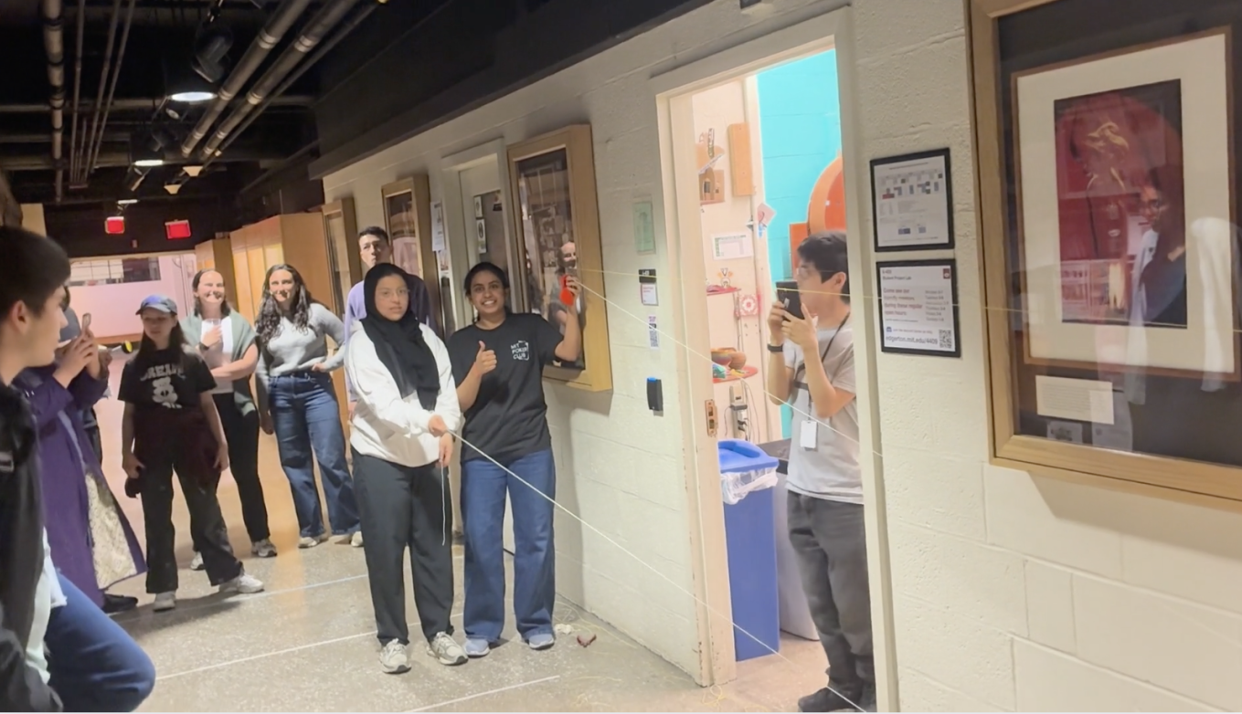 A group of students gathers at one end of Strobe Alley ready to watch an egg travel a pulley system down the hallway.