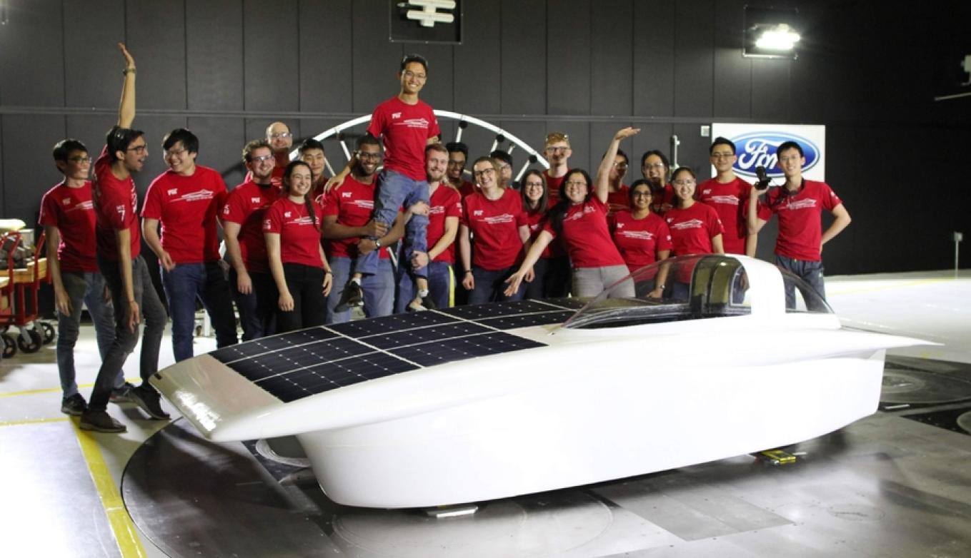 Solar Car team members stand on and around their sleek vehicle