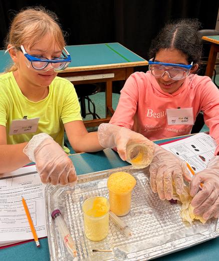 two high school students mixing chemicals in beakers
