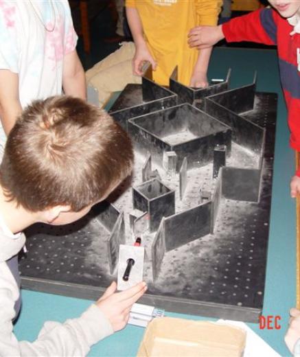 group of children setting a laser pointer into an oversize maze