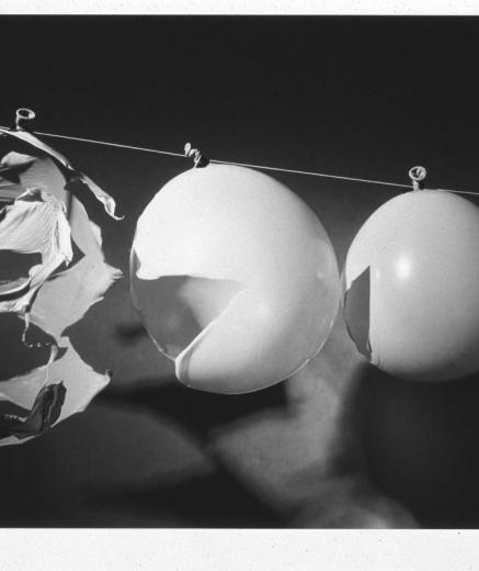 A bullet pieces three balloons in sequence, showing different degrees of popping
