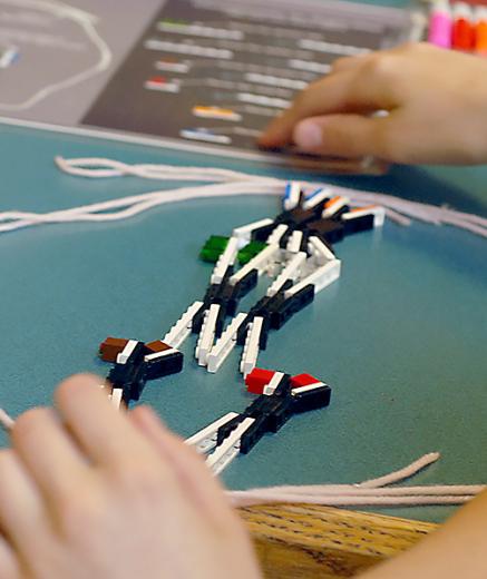 hands assembling LEGO model of chromosomes