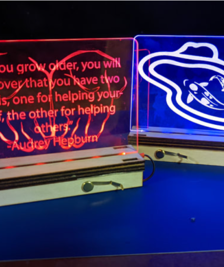 two light-up acrylic panels - the first shows hands with quote "as you grow older, you will discover that you have two hands, one for helping yourself, the other for helping others." - Audrey Hepburn. The other shows two Koi fish in a pond from above