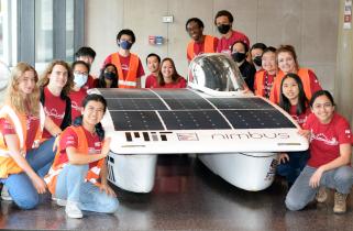 Members of the Solar Electric Vehicle Team posing around their car in Lobby 13