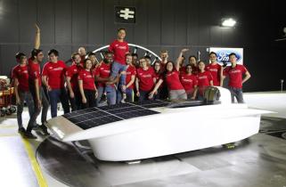 Solar Car team members stand on and around their sleek vehicle