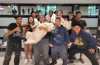 a group of students and instructors smiling for the camera, two holding large white dogs