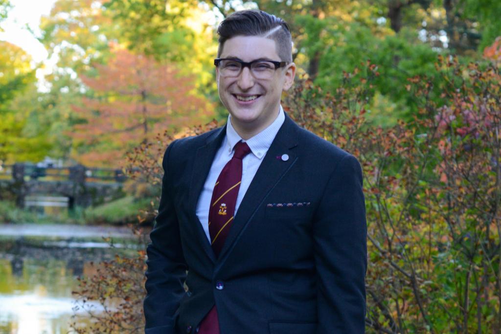 Sonny smiling, wearing a suit and tie against a fall backdrop