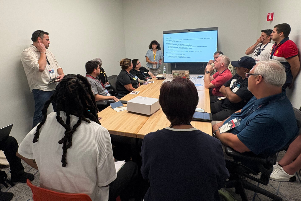Educators and makerspace leaders sit around a conference table while 