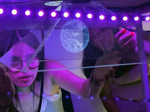 An EDW participant peers through purple lights to a hologram of Earth