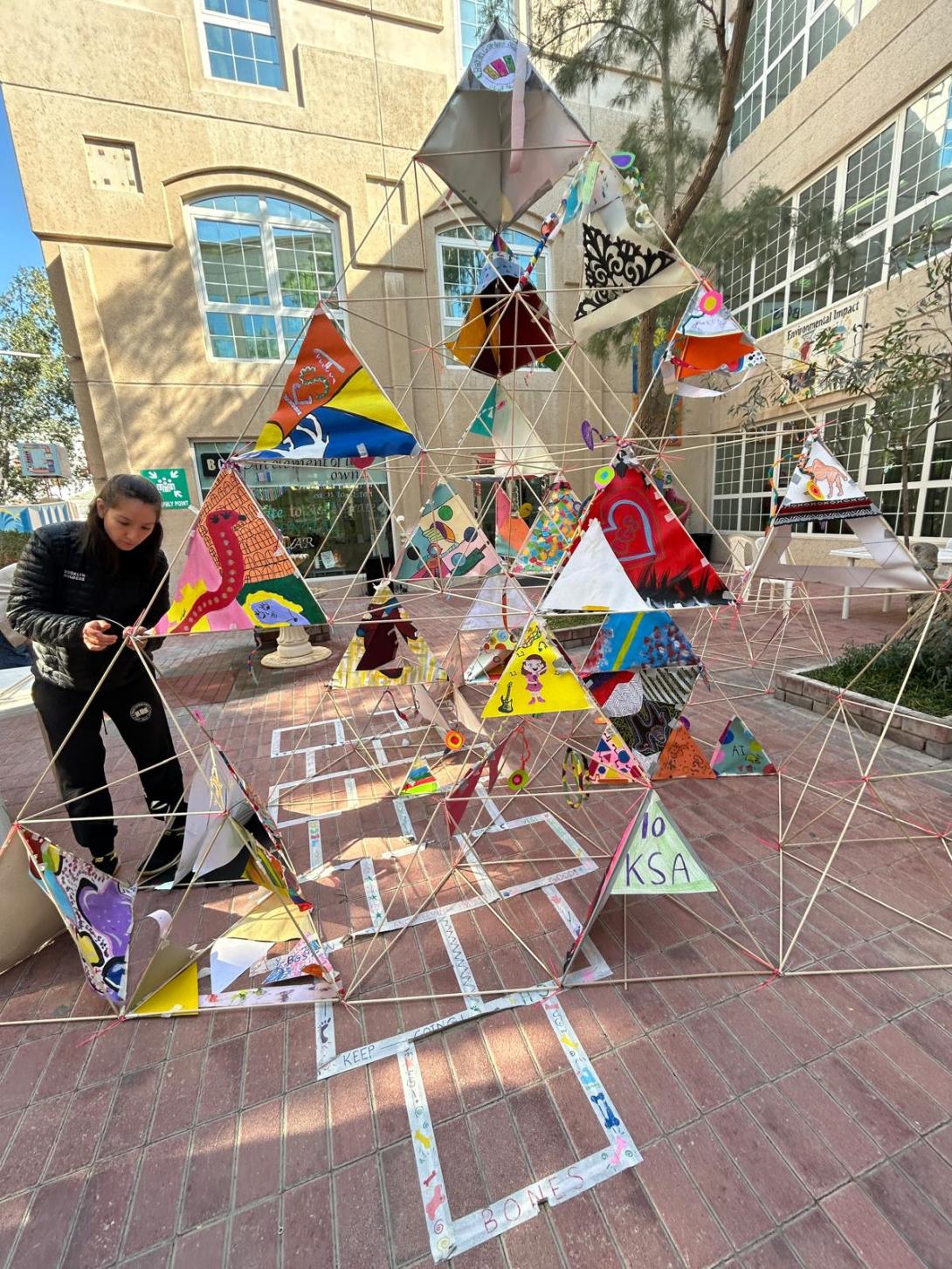 Triangles, some mirrored, some with art, and some with open space, come together to form a community tetrahedron